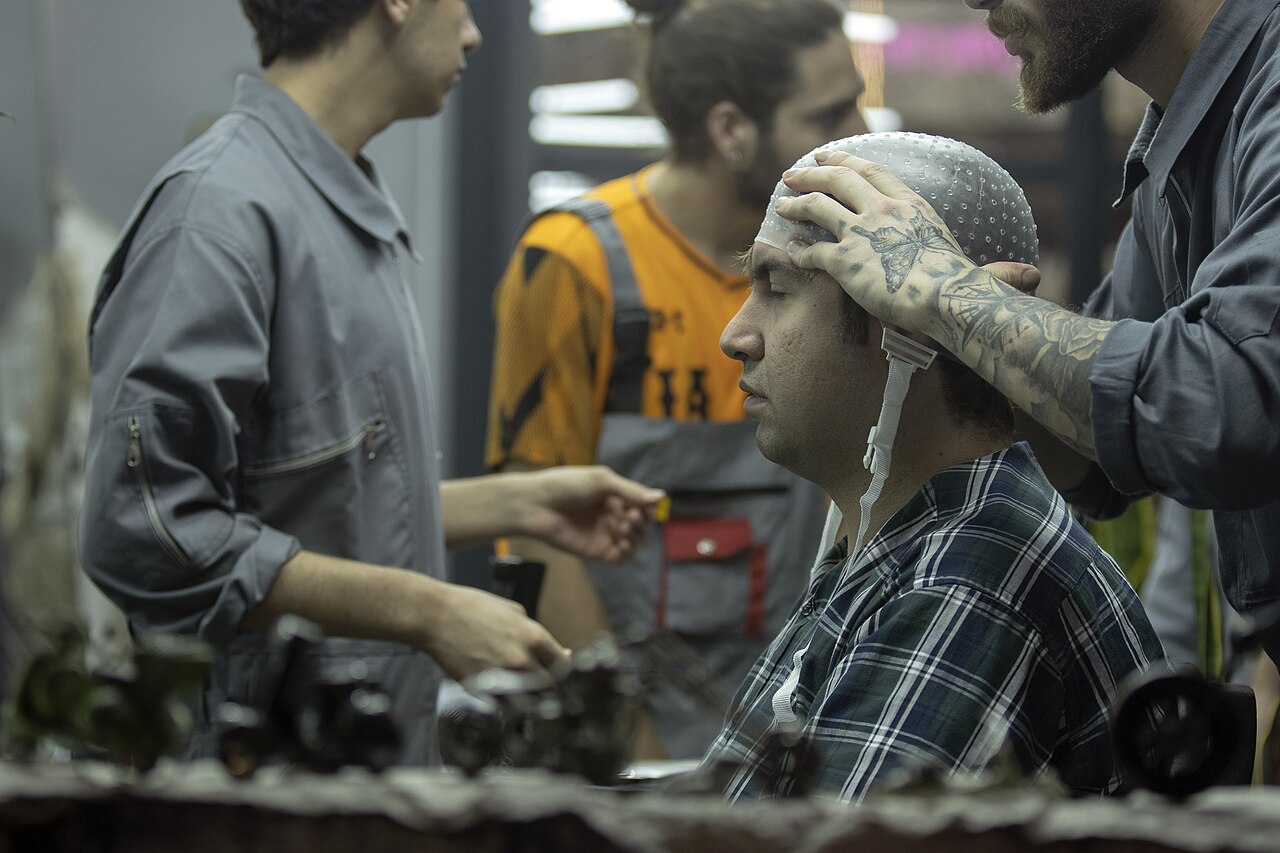 Stylist fitting a highlighting cap during a salon color service.